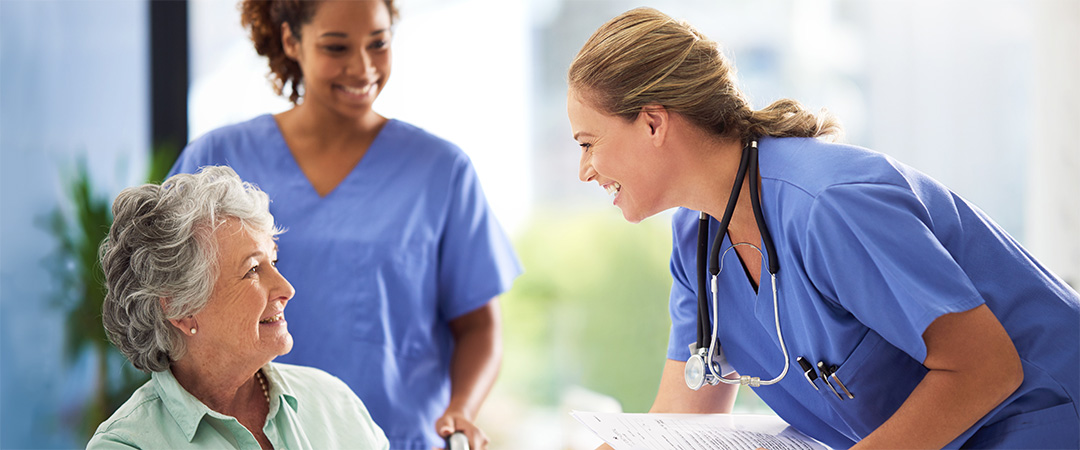 Senior woman smiling with skilled nurses.